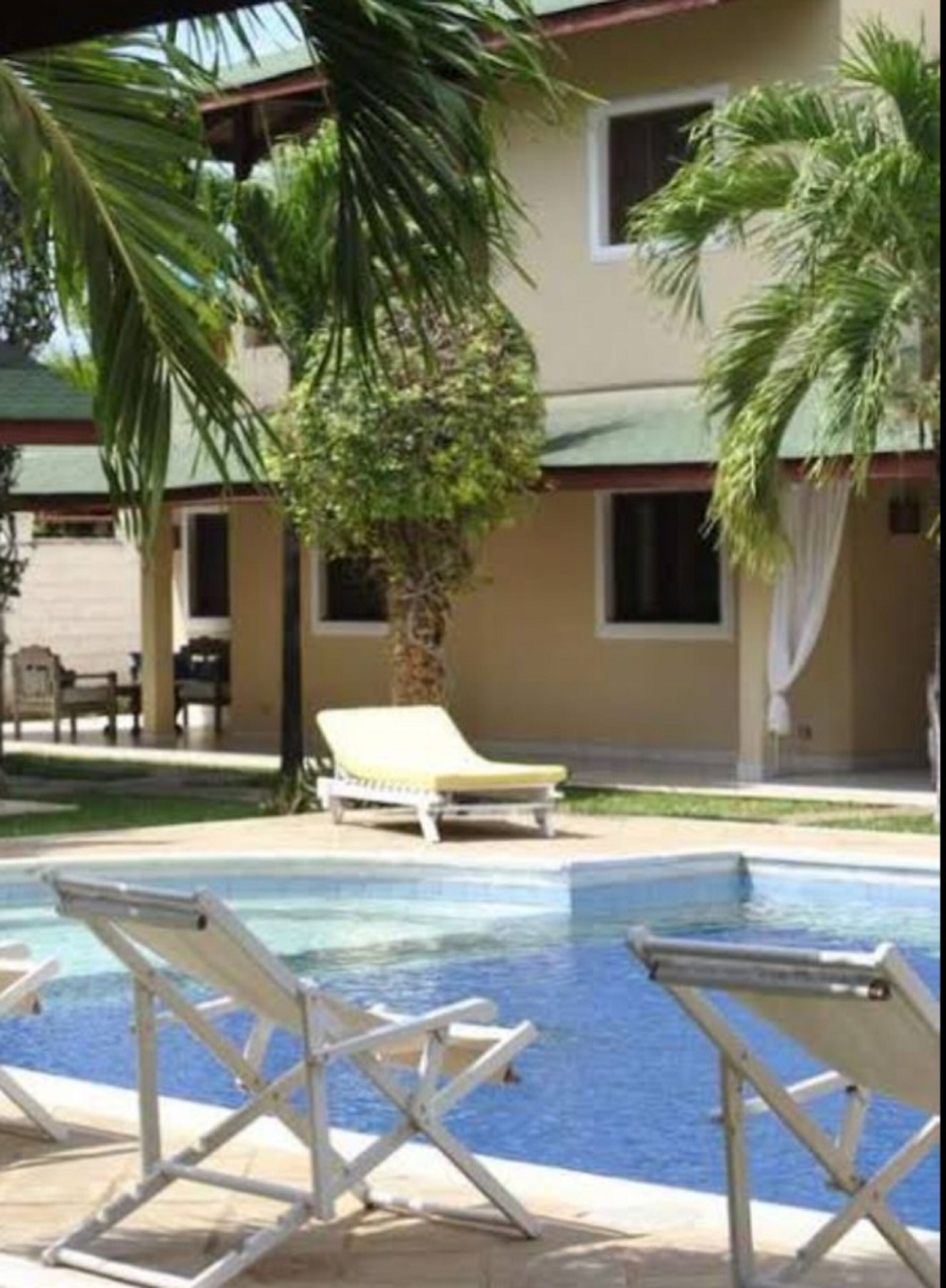 A pool area with lounge chairs and palm trees.