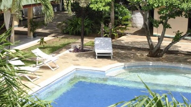 A swimming pool with lounge chairs and a small garden area. - Girasoli Hotel (Malindi)