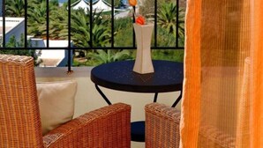 A balcony with wicker furniture, a small table with a vase and a drink, and a view of the sea and distant mountains. - Villa Helios with private pool, beautiful sea view and sunny terrace (Agios Nikolaos Lassithi)