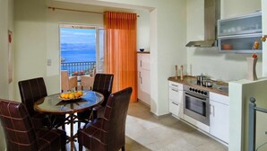 A modern kitchen with a stove, oven, and a dining area with a table and chairs. - Villa Helios with private pool, beautiful sea view and sunny terrace (Agios Nikolaos Lassithi)
