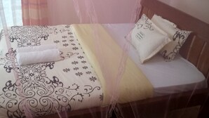 A bed with a canopy, patterned bedding, and pillows.