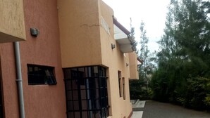 A building with a beige facade, a tiled entrance, and a gravel driveway.