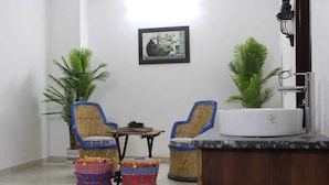A small, clean room with two wicker chairs, a small table, and a white sink.