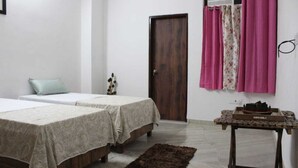 A bedroom with two beds, a wooden door, a small table with a tray, and a rug.