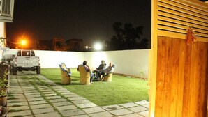 A patio area with a white wall, a wooden gate, and a parked vehicle.