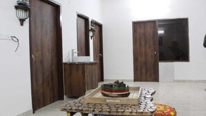 A room with a wooden door, a small table with a model ship, and a window.