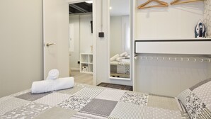 A hotel room with a neatly made bed, a wardrobe, and a mirror reflecting the bed and a neatly made bed in the adjacent room. - Stay U-nique Apartment Llobregat (L'Hospitalet de Llobregat)