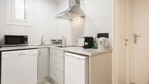 Una cocina moderna con armarios blancos, microondas, cafetera y lavavajillas.