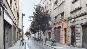 Une rue bordée d’immeubles, avec un arbre et un scooter garé.
