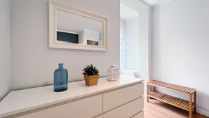 A modern bathroom with a white vanity, a mirror, a blue vase, a potted plant, and a wooden shelf. - Stay U-nique Apartment Travessera (Barcelona)