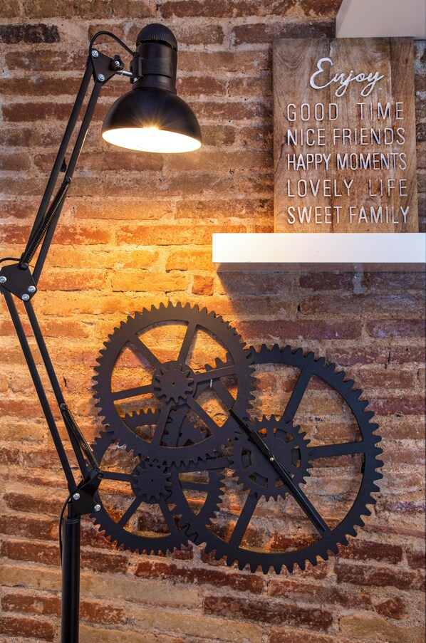 Uma luminária de mesa fixada na parede, com um detalhe de engrenagem de metal e uma placa com uma frase motivacional.