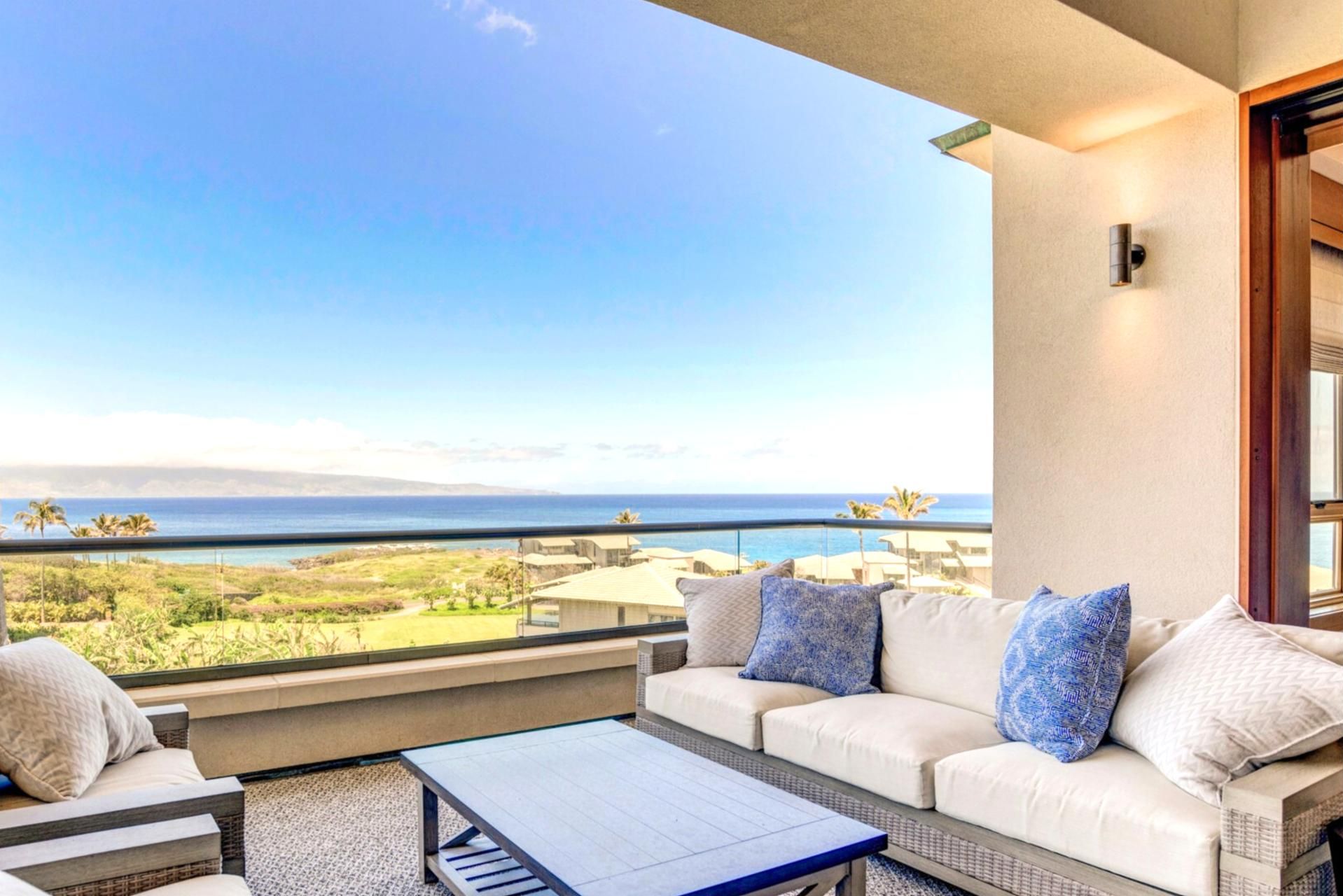 A balcony with a view of the ocean, a sofa with cushions, and a coffee table.