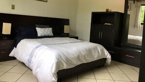Una habitación de hotel con cama, mesitas de noche, un armario y un espejo.