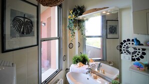 A bathroom with a large window, a sink, a mirror, and decorative wall tiles. - Casa Papaveri e Conchiglie (Riccione)