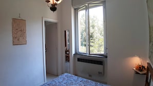 A bedroom with a bed, a window, a radiator, and a wall-mounted light fixture. - Casa Isotta (Bonassola)
