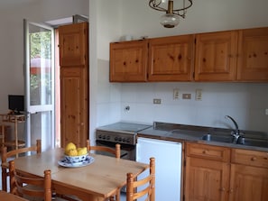 Una cocina con armarios de madera, estufa, fregadero y una mesa de comedor con sillas.
