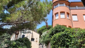 A building with a curved tower, a staircase leading to a door, and surrounding greenery. - Casa Isotta (Bonassola)