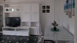 A modern living room with a flat-screen TV, white cabinetry, a dining table with chairs, and a hanging light fixture. - Welcome on Board (Levanto)