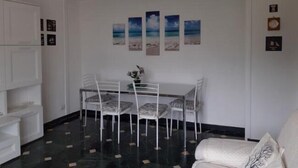 A dining area with a glass table and chairs, a chandelier, and a wall with framed pictures. - Welcome on Board (Levanto)