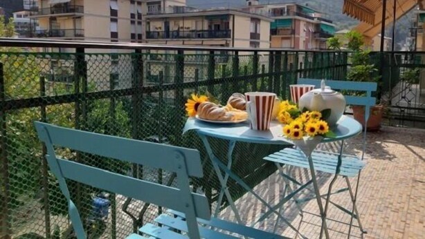 A balcony with a table set for breakfast, including pastries, a teapot, and cups. - Welcome on Board (Levanto)
