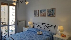 A bedroom with a bed, two bedside tables with lamps, a radiator, and three wall-mounted pictures. - Welcome on Board (Levanto)