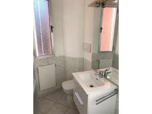 Ein Badezimmer mit Toilette, Waschbecken und Fenster.