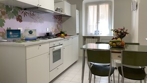 Une cuisine moderne avec des meubles blancs, une cuisinière à gaz et un coin repas comprenant une table et des chaises.