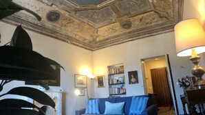 Un salon avec un canapé bleu, une cheminée et un plafond orné de motifs complexes.