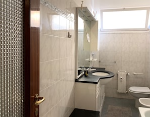 A bathroom with a toilet, sink, and mirror. - House Dinigi (Chiavari)