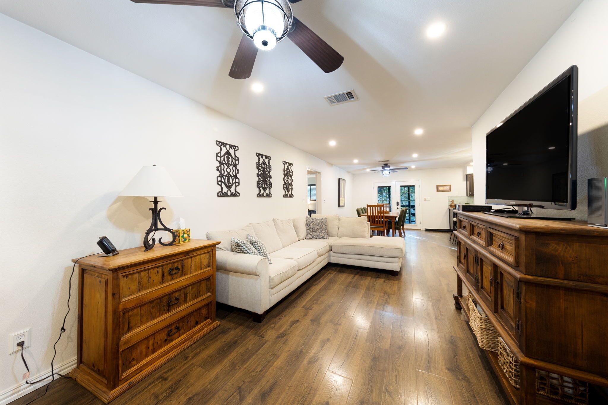A spacious living room with a sectional sofa, wooden entertainment center, and a flat-screen TV.