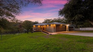 A modern house with a garage, a covered porch, and a well-maintained lawn. - Picturesque and Beautiful 3B on the Guadalupe River (New Braunfels)