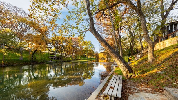 A tranquil riverside pathway with a wooden bench, stone steps, and a stone wall. - Picturesque and Beautiful 3B on the Guadalupe River (New Braunfels)