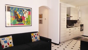A modern living room with a black sofa, colorful cushions, and a vibrant abstract painting on the wall. - Casa Ninni (Chiavari)