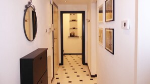 A hallway with a tiled floor, a mirror, a dresser, and framed pictures on the walls. - Casa Ninni (Chiavari)