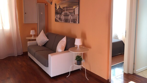 A living room with a sofa, a small table with a lamp, a potted plant, and a painting on the wall. - House Nervi (Genoa)