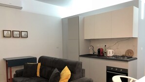 Una cocina compacta con un sofá, una mesa de comedor y una pequeña alfombra.