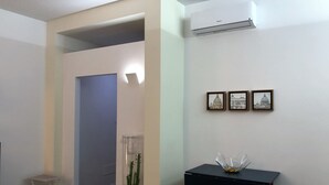 Una sala de estar moderna con un sofá negro, una mesita negra con un cuenco de vidrio y tres cuadros enmarcados en la pared.