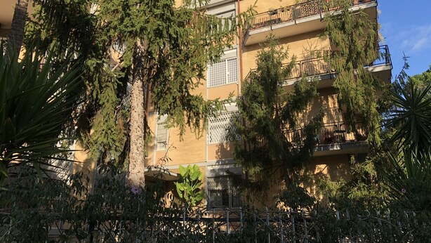 Un edificio de varios pisos con balcones, algunos con plantas.