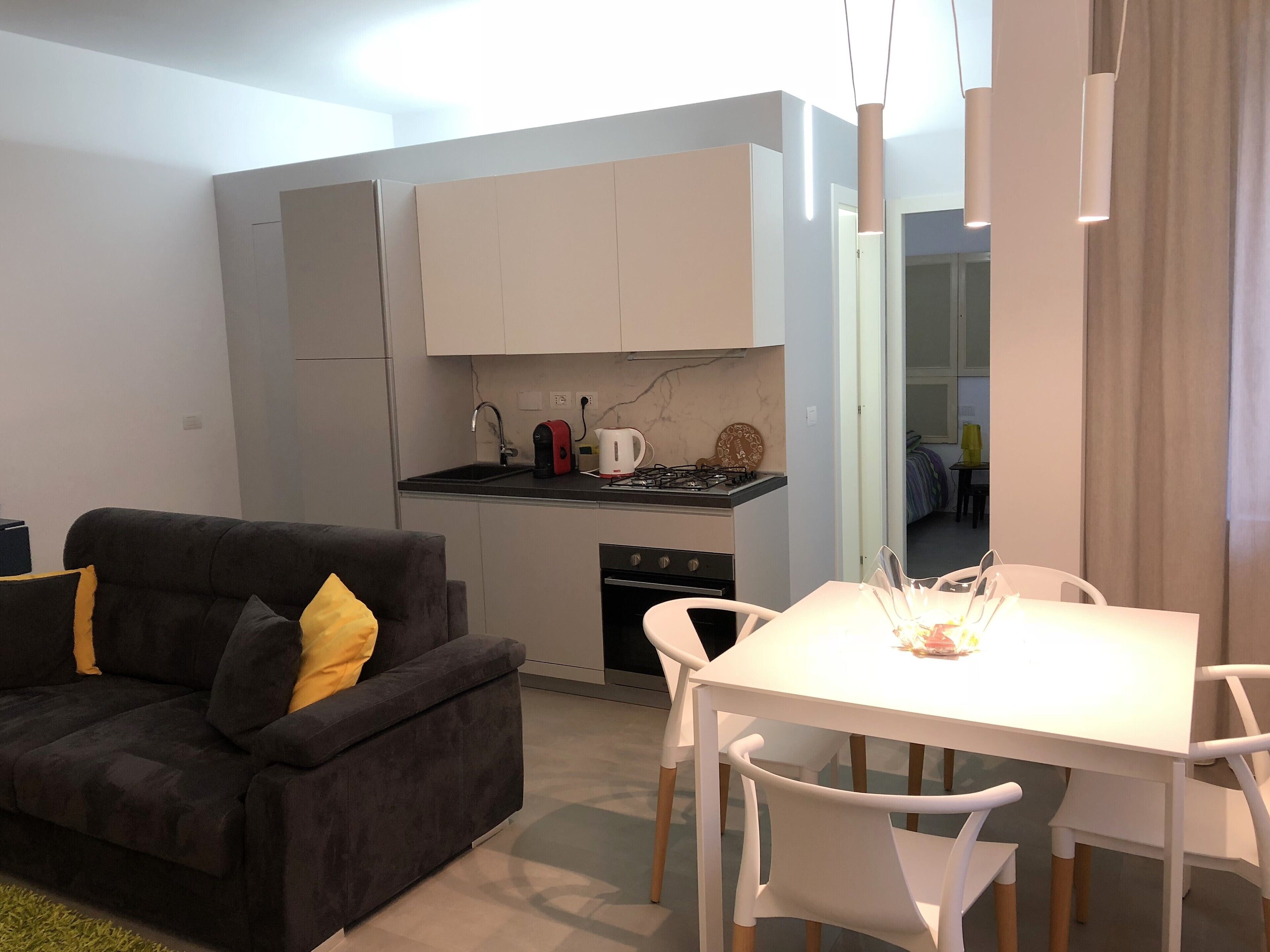 Un espacio habitable compacto con kitchenette, zona de comedor y sofá.