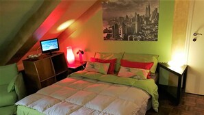 A bedroom with a bed, a desk, a chair, a TV, and a cityscape poster on the wall. - Sotto la Mole (Turin)