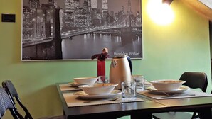 A dining area with a table set for two, a large poster of the Brooklyn Bridge, and a kettle on the table. - Sotto la Mole (Turin)