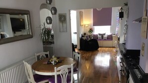 Uma cozinha moderna com área de jantar, piso de madeira e vista para a sala de estar.