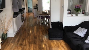 Uma sala de estar moderna com um sofá preto e uma área de jantar com mesa e cadeiras.