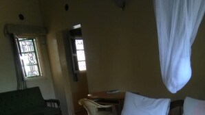 A hotel room with a bed, a green sofa, a desk, and a chair. - Magline Conference And Guest House (Kisumu)