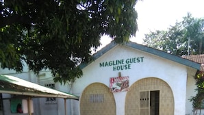 A building labeled "Magline Guest House" with a simple, arched entrance and a small porch area. - Magline Conference And Guest House (Kisumu)