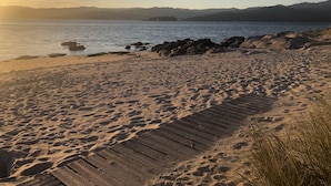 A beach with a wooden boardwalk leading to the water, surrounded by sand and rocks. - OH LA LIFE  PORTOSIN LA PLAYA Beachfront (Portosin)