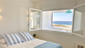 A bedroom with a bed, a window with a view of the beach, and a small table with a plant. - OH LA LIFE  PORTOSIN LA PLAYA Beachfront (Portosin)