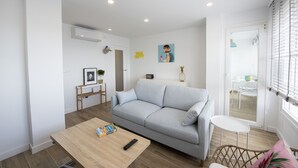 A modern living room with a light grey sofa, a wooden coffee table, and a small white table. - OH LA LIFE  PORTOSIN LA PLAYA Beachfront (Portosin)