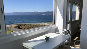 A balcony with a white table and chairs, a view of the sea, and a clear sky. - OH LA LIFE  PORTOSIN LA PLAYA Beachfront (Portosin)