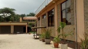 A building with a paved courtyard, potted plants, and a covered area. - Matteo's Resort (Naivasha)